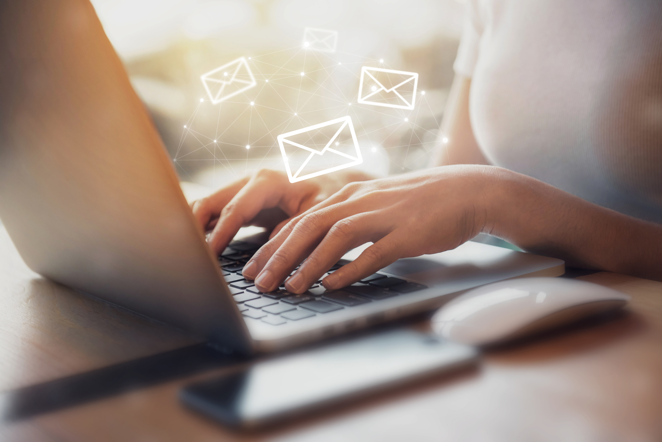 Person writing marketing emails on a laptop with email icons displayed
